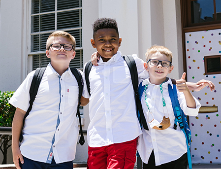 Three school boys posting for a picture with their backpacks on their shoulders