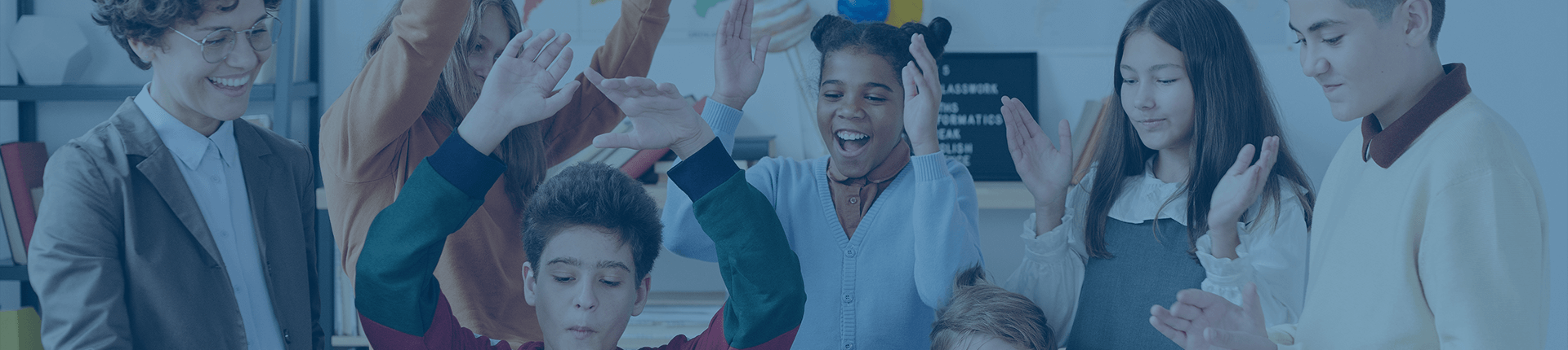 group of young children in a classroom clapping and arms raised in the air